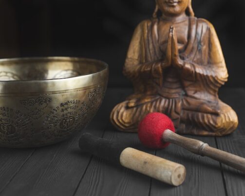 Photo of Buddha statue next to a singing bowl and mallets.